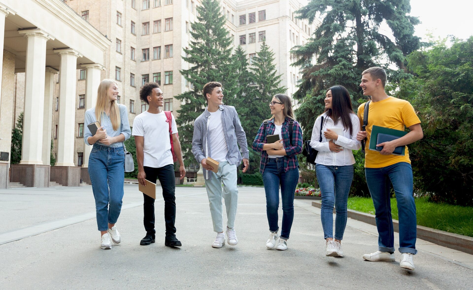 Happy students walking outside the university building