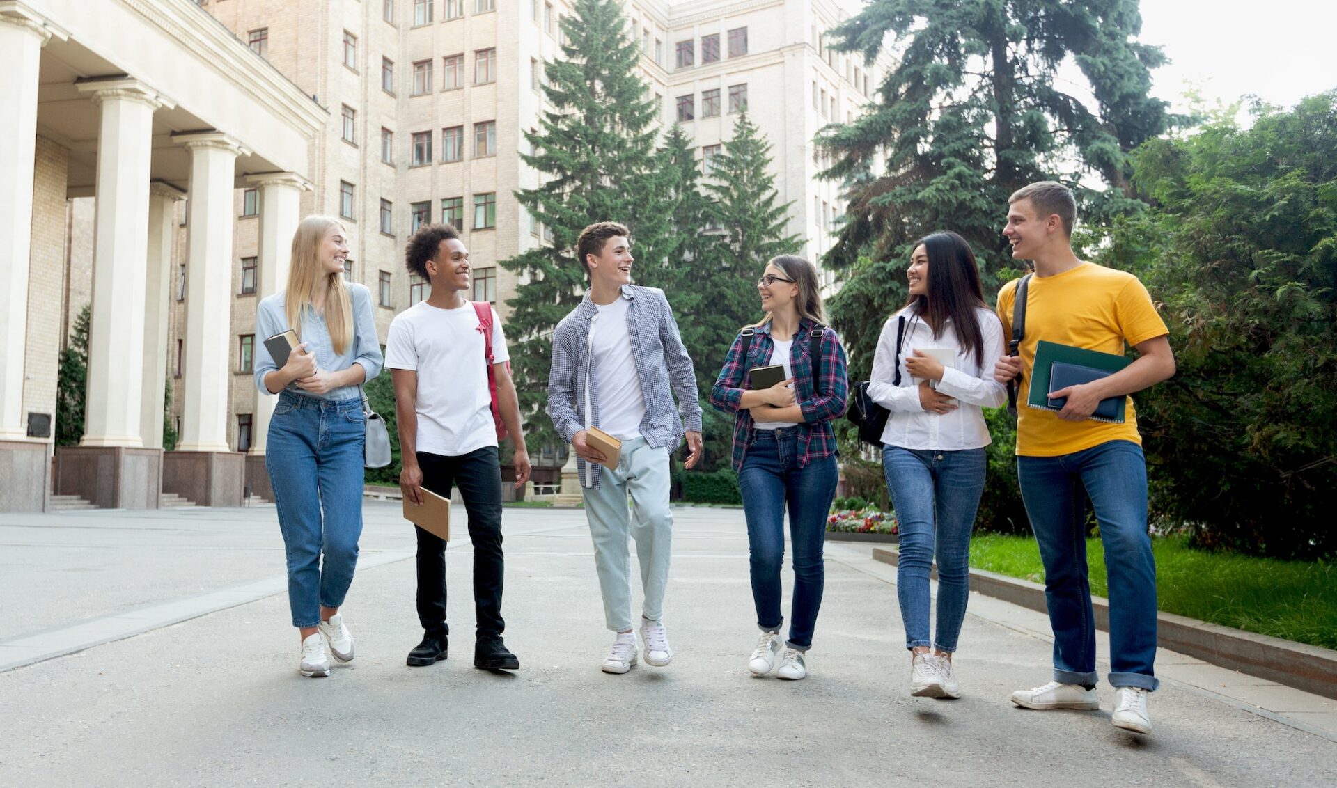 Happy students walking outside the university building